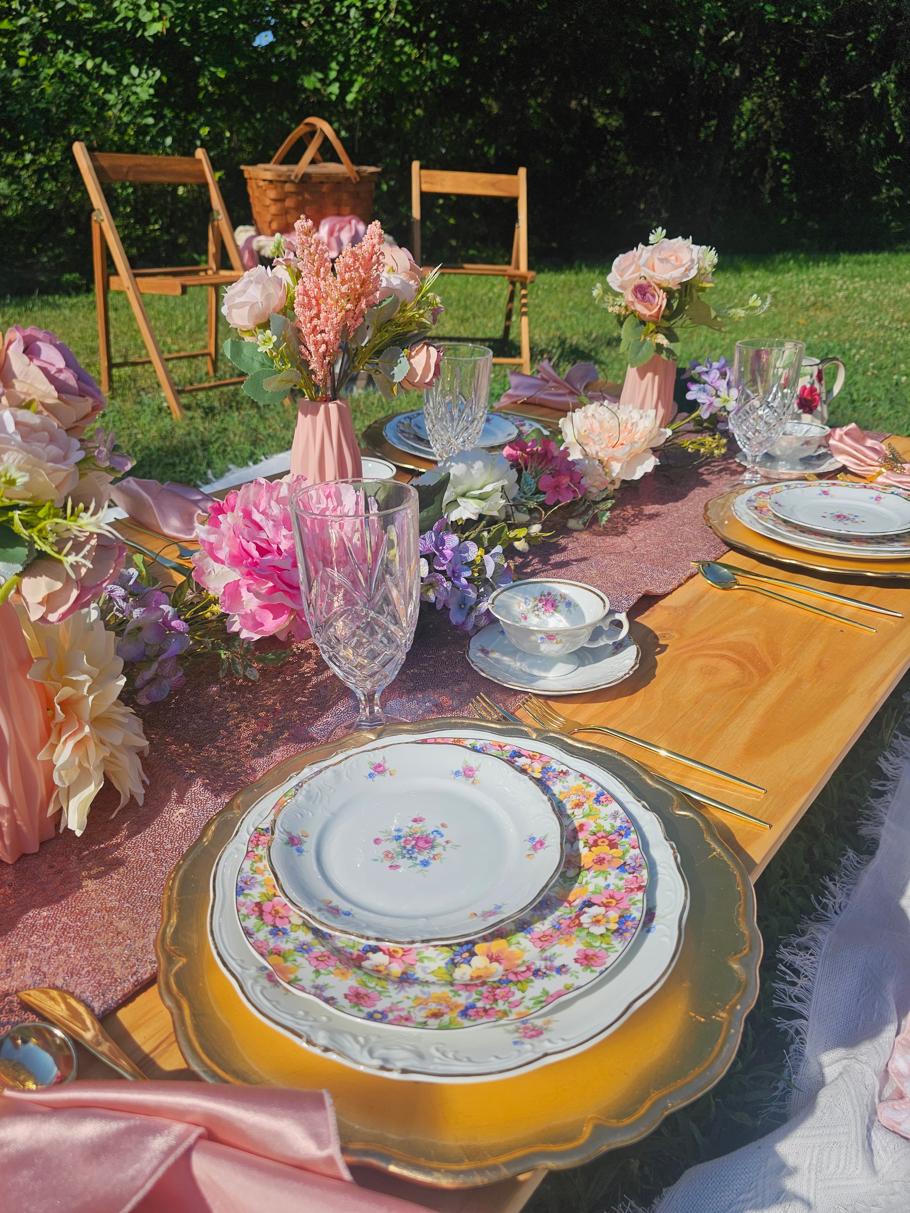An outdoor table setting with pink florals and vintage china
